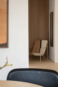 A modern residential interior featuring wooden furniture and a fabric chair with a black stripe.