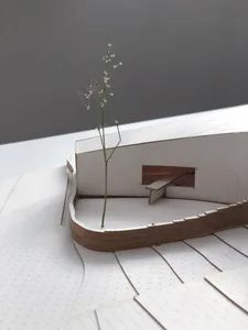 A paper model of a building with a small plant growing through the floor.
