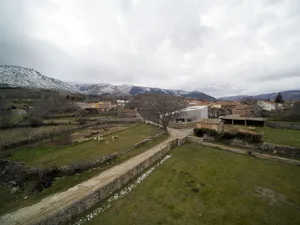 A view of a village in winter with snow-covered mountains in the background.