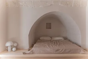 A minimalist bedroom with a concrete wall and built-in bed.