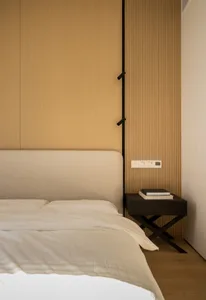 A minimalist bedroom featuring a bed with a fabric headboard and a nightstand with books and reading materials.