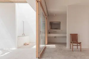 Modern minimalist bathroom with concrete walls and floor, natural light, and wooden accents.