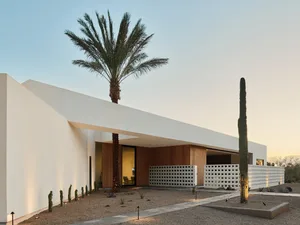 Modern minimalist home featuring white concrete walls and glass walls.