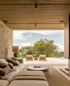 A minimalist living room featuring wood and stone materials with a comfortable seating area and a view of the outdoors.
