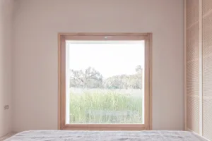 A minimalist room with a window overlooking a lush green field.