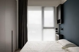 A modern bedroom with a bed, windows, and grey curtains.