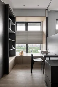 A modern home office featuring a wooden desk with a view of the cityscape outside the window.