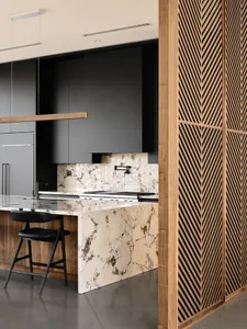 A modern kitchen featuring marble countertops and backsplash, with dark cabinets and a wooden slat wall.