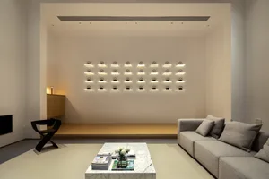 Modern minimalist living room with a white marble coffee table, gray sectional sofa, and wall-mounted lighting