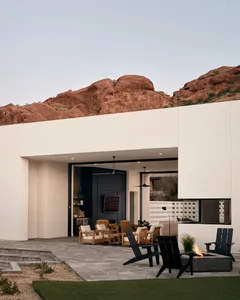 Concrete exterior of a modern residential building with red rock formations in the background.