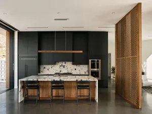 A modern residential kitchen with black wood cabinets and a marble countertop.