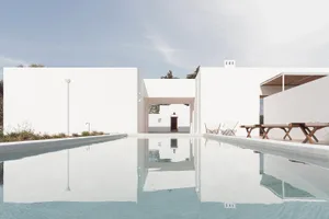 Modern white cube house with concrete exterior and reflecting pool.