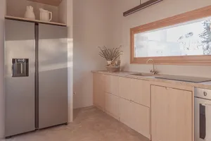 Modern minimalist kitchen featuring sleek glass cabinets and stainless steel appliances.
