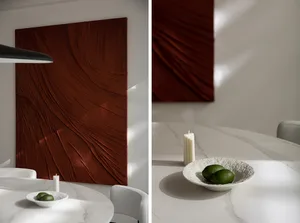 A minimalist interior with marble finishes, featuring a textured art piece and a lit candle.