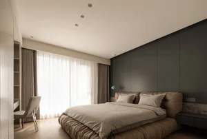 A minimalist bedroom with a taupe-colored bed and curtains.