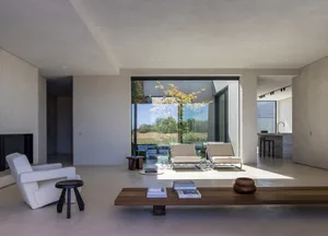 A minimalist living room with neutral materials and a view of the outdoors.