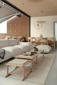 Minimalist living room featuring white and beige furniture, wood coffee tables, and a large beige rug.