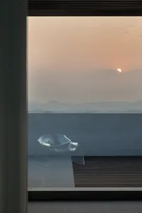 Transparent glass chair on a patio at sunset