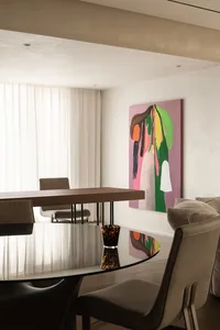 A modern dining room featuring a glass and wood table, leather chairs, and a colorful abstract painting on the wall.