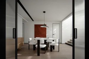 Modern dining room with metal table, white leather chairs, and minimalist decor.