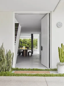 Modern entrance with concrete floor, minimalist design, and greenery.
