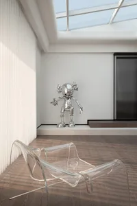 A minimalist interior design featuring a clear glass chair and a metallic robot sculpture.