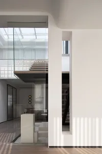 Modern interior with glass staircase, concrete steps, and black metal accents.