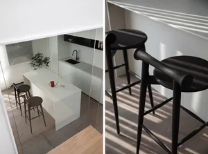 Modern kitchen featuring white marble countertops and black wood stools