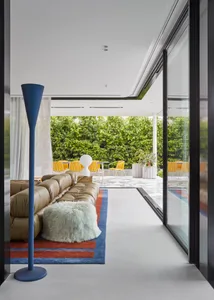 Modern living room with a concrete floor, glass sliding doors, and a green fur blanket.