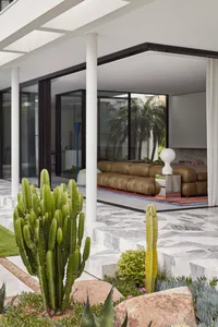 Modern living room with concrete floor, glass walls, and marble accents.