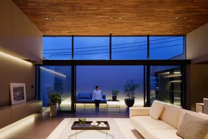 A modern living room featuring glass panels, white sofas, and a cozy atmosphere.