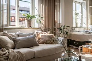 Modern living room featuring natural fiber textiles, wood accents, and potted plants with light curtains