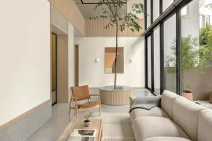 Modern living room with a terrazzo floor, minimalist decor, and a central tree.