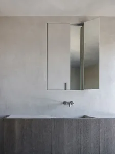 Modern minimalist bathroom featuring a concrete countertop and wooden cabinetry.