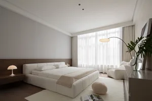A modern minimalist bedroom featuring a white bed, textured fabric, and white curtains with a sleek floor lamp.