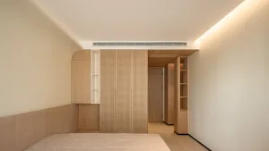 Minimalist bedroom interior with wooden cabinets and a bed.