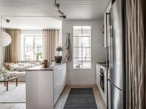 Modern, minimalist kitchen featuring white cabinets and stainless steel appliances.