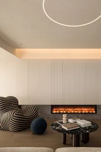 A modern minimalist living room featuring a marble fireplace and coffee table with books and decorative items.