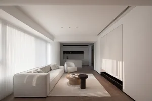A minimalist living room with white furniture, featuring a comfortable sofa, a coffee table, and a sleek, modern design.