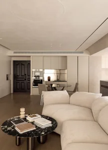 A modern residential interior with a minimalist design, featuring neutral tones and a neutral-colored sectional sofa.