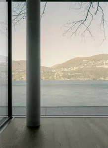 Modern architectural view featuring glass walls, concrete flooring, and a scenic landscape.