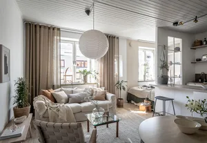 A minimalist apartment living room with neutral-toned decor and plants.