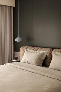 A well-designed minimalist bedroom with a fabric bed and wood accents.