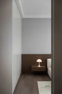 A minimalist bedroom featuring a wooden floor, a modern table lamp, and a white sofa.