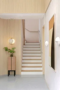 Modern interior with white stairs, wooden floor, and light fixture
