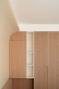 A modern, minimalist wooden cabinet with perforated panels and an integrated display shelf.