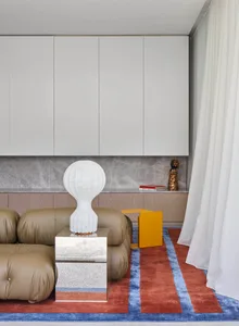 A modern living room featuring a taupe leather couch, silver coffee table, and white floor lamp.