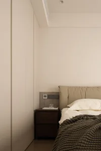 A modern, minimalist bedroom with neutral color palette and simple furnishings.