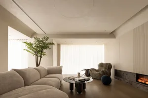 Modern interior design featuring a comfortable couch, a unique striped armchair, a round glass coffee table, a built-in firep
