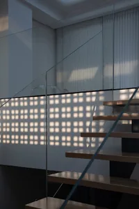 Modern wooden staircase photographed from above with glass railings, showcasing clean lines and contemporary design.